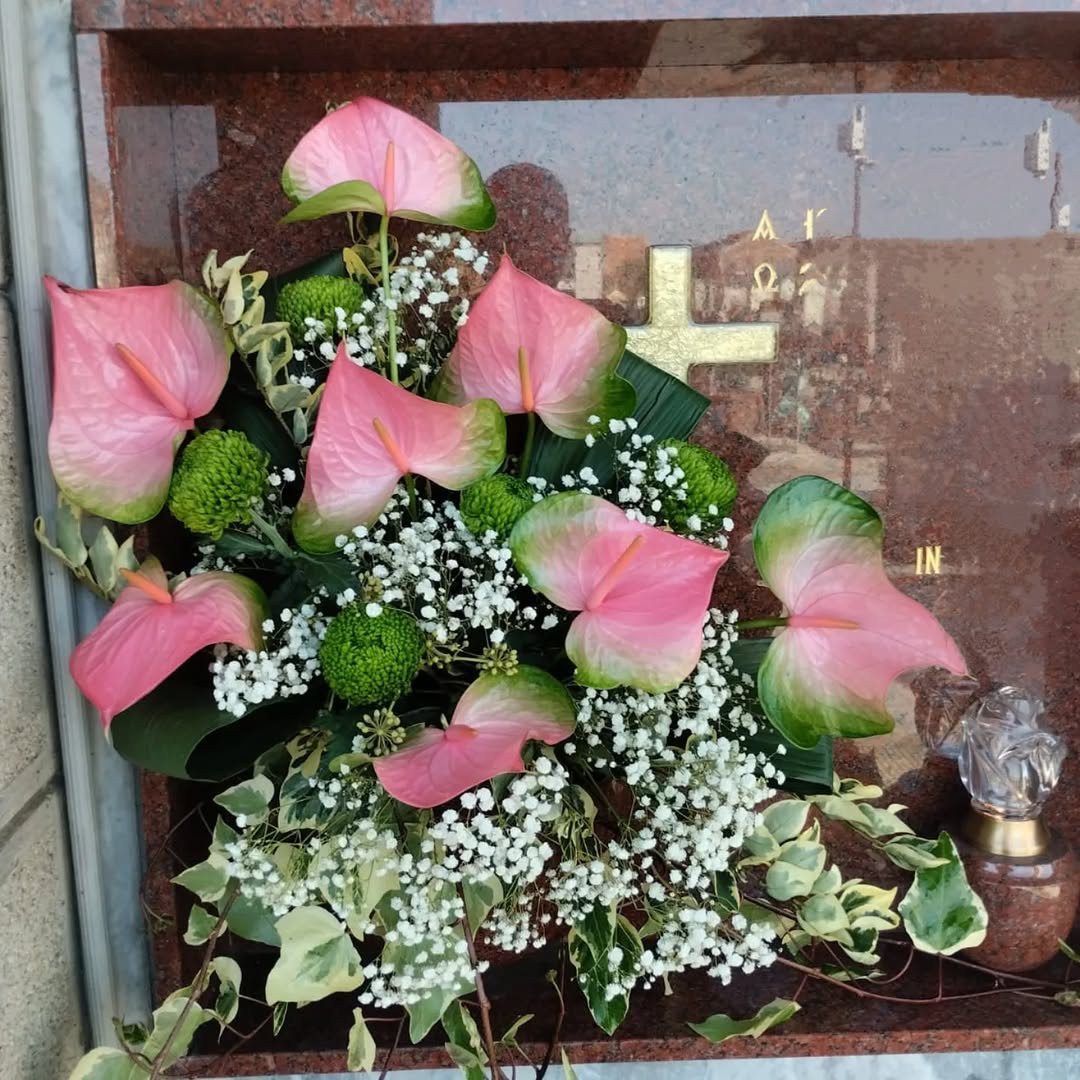 Composizione di anthurium rosa, crisantemi e velo da sposa su una lapide
